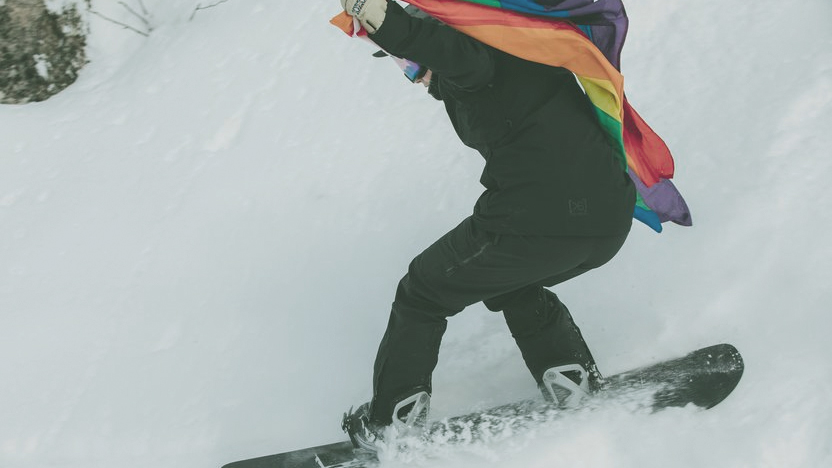 a snowboarder with a rainbow flag