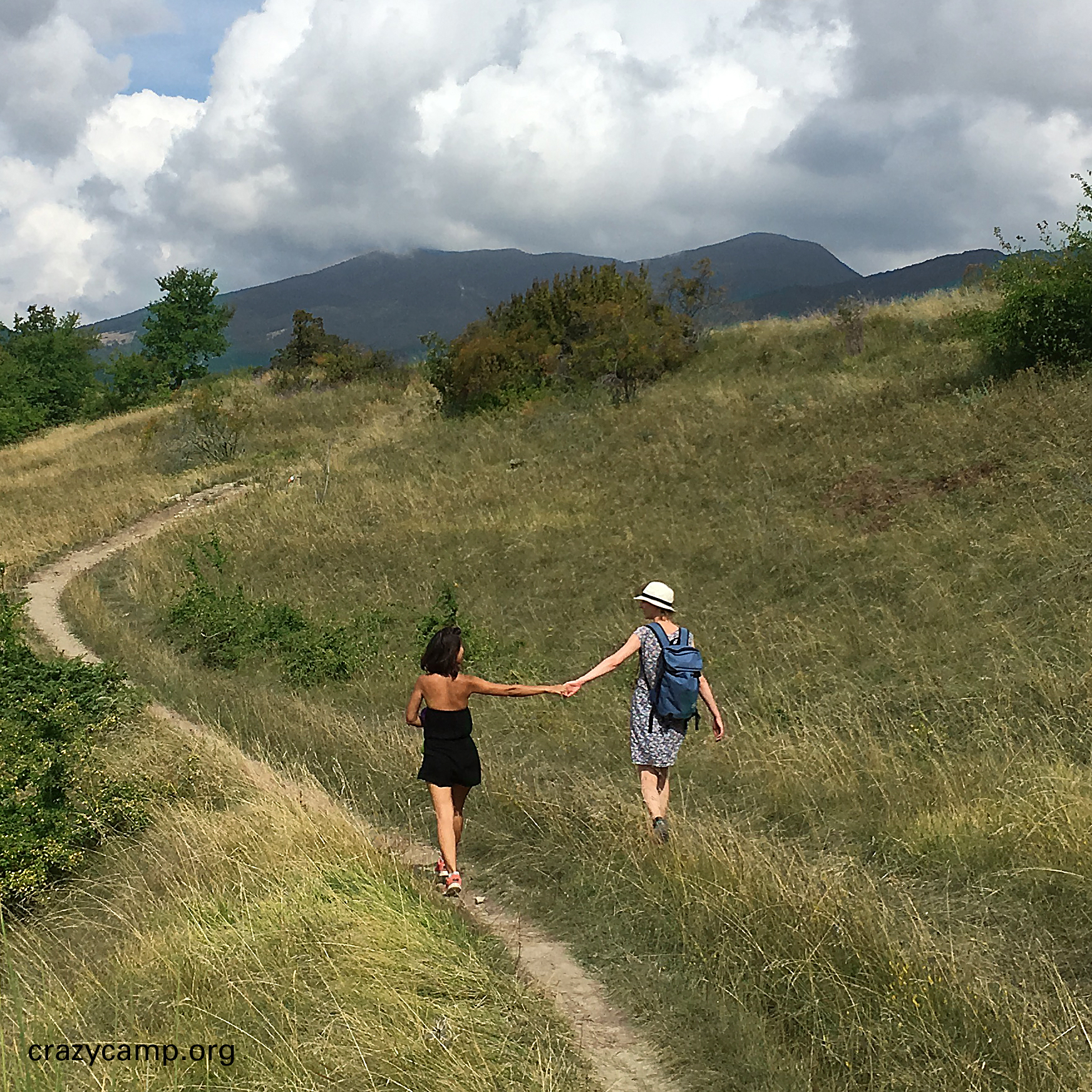A photo of two women, holding hands while hiking