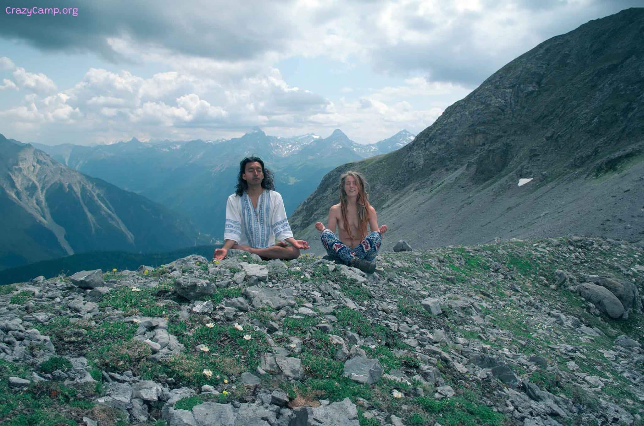 Featured image representing the Crazy Mountain Balance Camp 2024. It is a photo pf a man and a woman seated in lotus on a mountain ridge, they seem to be meditating.